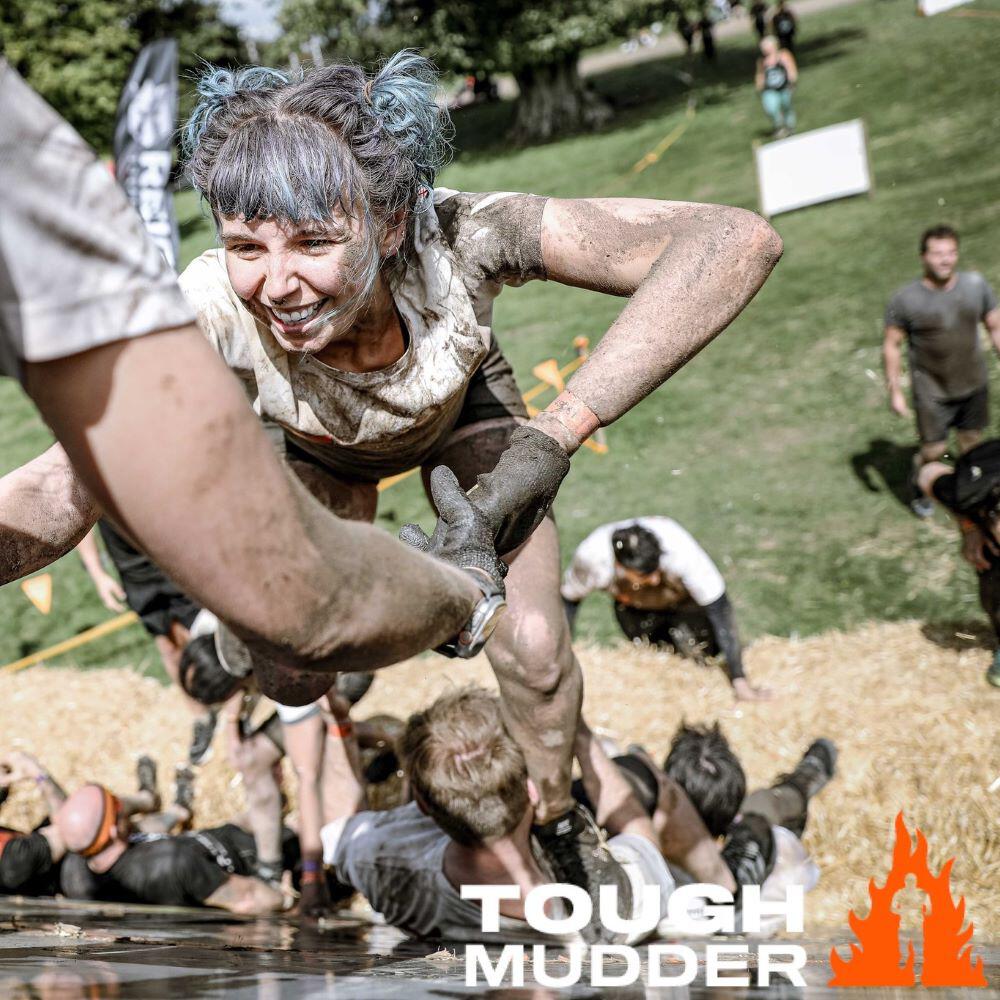 Smiling woman taking part in Tough Mudder with a teammate