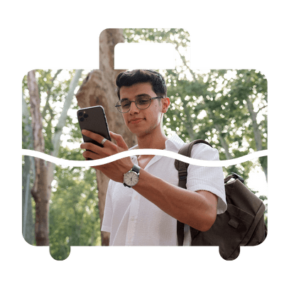 Travelling man surrounded by trees. He is using a mobile and smiling. The image is contained within a suitcase shaped frame.