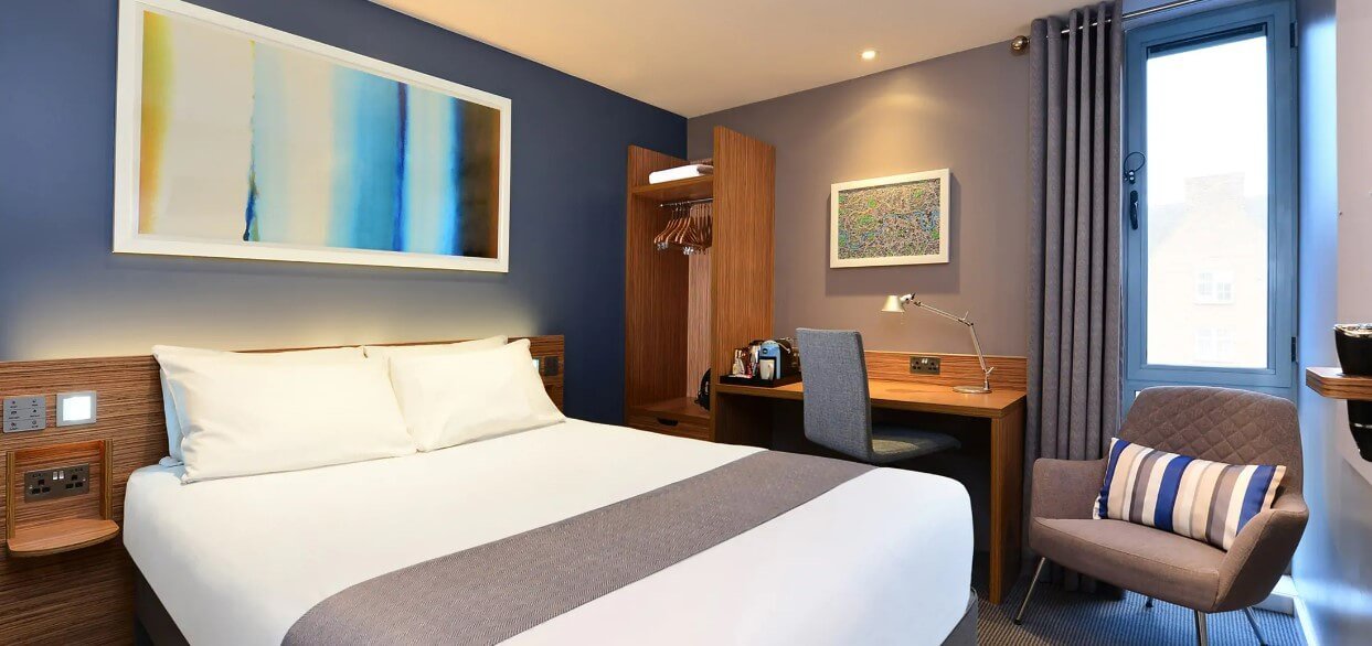 Travelodge plus room featuring bed, chair and wardrobe