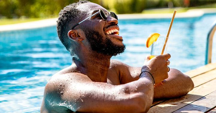 TUI winter banner showing a man enjoying a drink while at the side of a swimming pool in sunny location