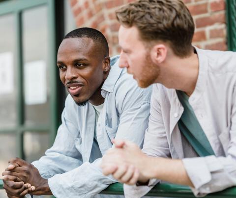 two guys leaning on a wall chatting about health issues