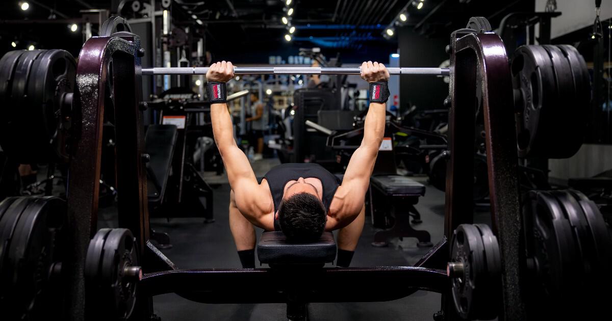 Man lifting barbell with Versa Gripps in gym