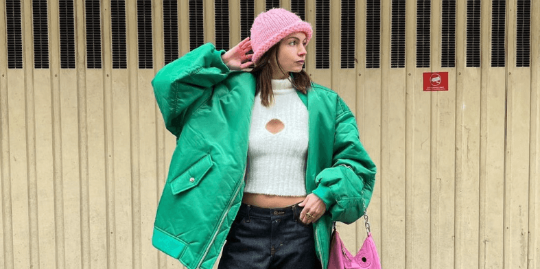 Vestiaire Collective deals page banner - Woman wearing a bright green jacket and pink hat in front of a shutter