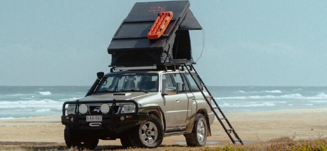 VicOffroad deals page image - A hatchback car on a beach with black tent on the roof