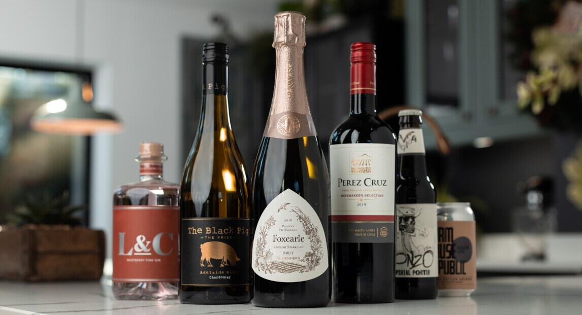 Virgin Wines savings tips banner Image - A selection of wine and spirit bottles on a counter top in a kitchen setting