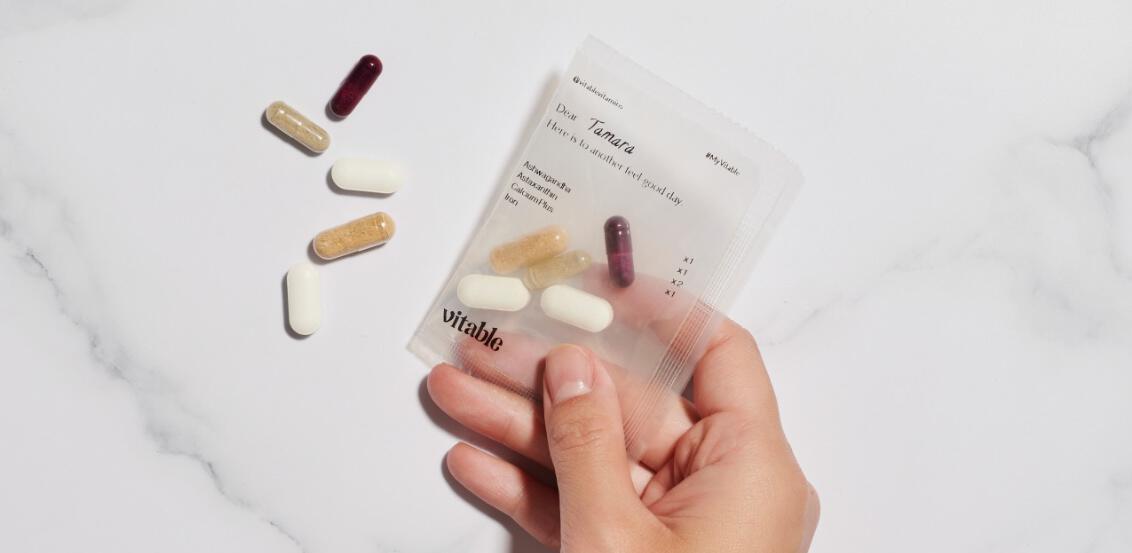 Vitable ways to save image, featuring a hand holding a pack of Vitable with vitamins spilling out onto a marble surface