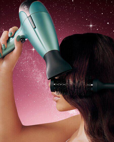 Woman using black ghd hair dryer to style hair