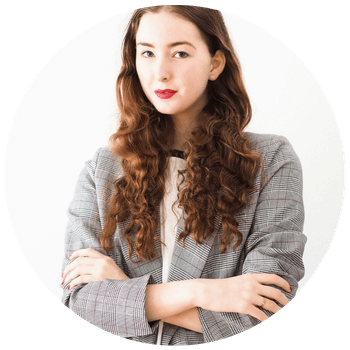 Woman with arms crossed wearing a grey blazer