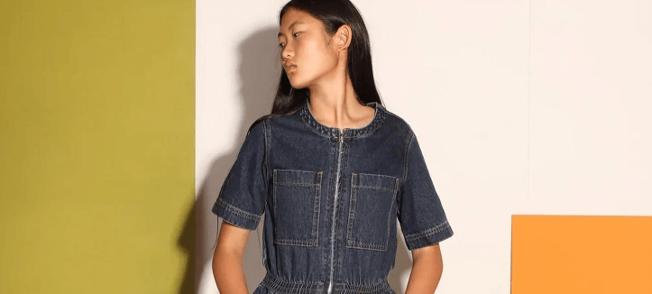 Young British Designers page banner - Top half of a woman wearing a denim jumpsuit in front of a colourful background
