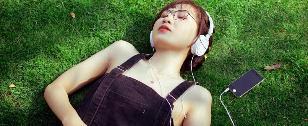 Young person listening to music in park