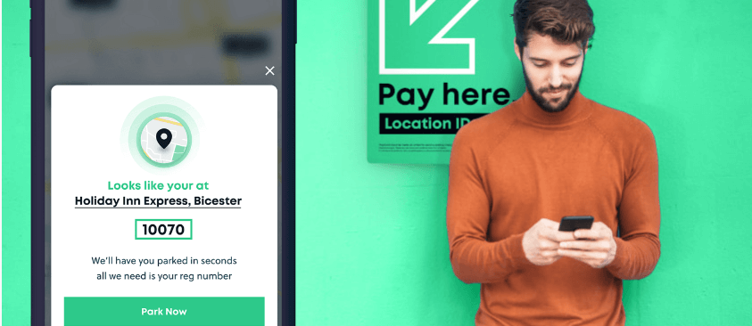 image of man in an orange sweatshirt holding a phone with a zoomed in parking app screen to the left of him