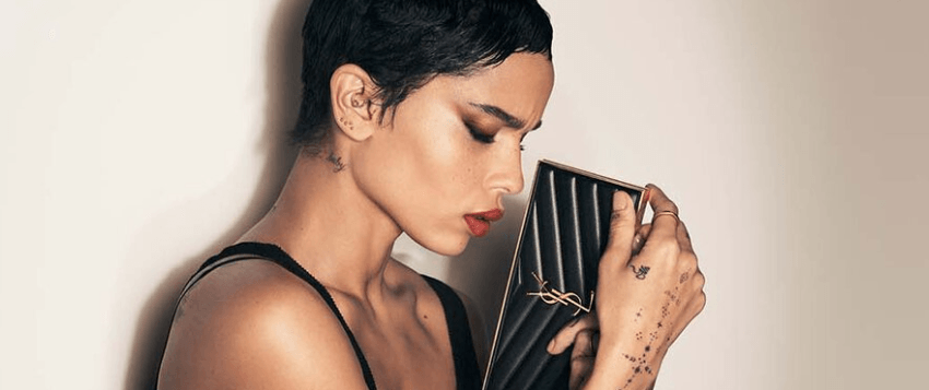YSL Beauty savings guide banner featuring a woman in makeup clutching a powder compact